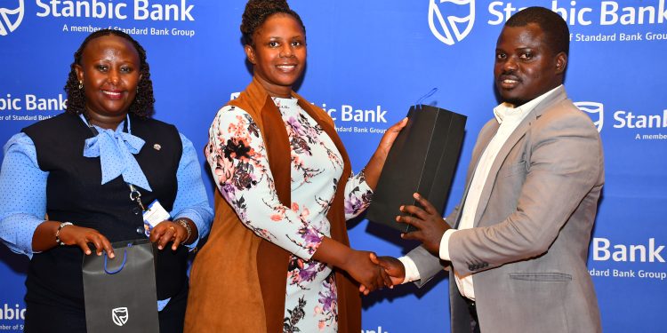 Sylvia Atuhairwe (C), the Stanbic Head of Distribution handing over a gift to one of the SACCO leaders