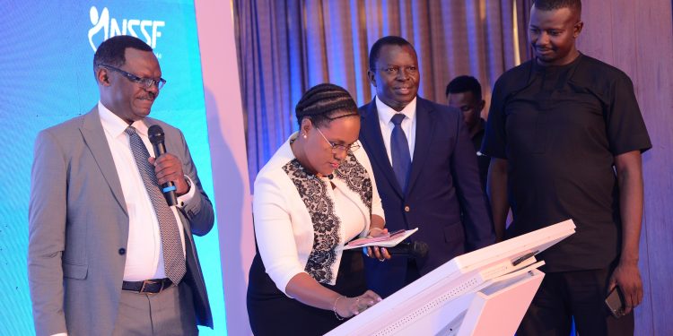 L-R Patrick Ayota, the Managing Director NSSF Uganda, Dr David Ogong Board Chairman and Thadeus Musoke the KACITA Chairman look on as a customer opens an account on Smartlife Flexi