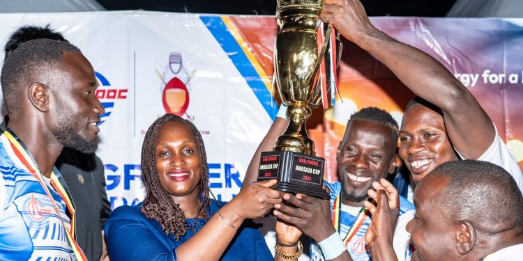 Aminah Bukenya Ag Head of Corporate Affairs Department shares a light moment with Buhanguzi County team who are the winners of the 2024 Amasaza Cup Tournament