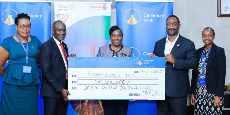 Joseph Balikudembe (2nd right) the Executive Director of Centenary Bank hands over a 100 million dummy cheque to Rtn Ann Nkutu the District Governor of D9213, at Mapeera House