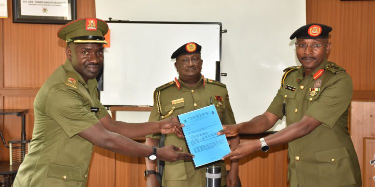 (L-R) Maj. Bilal Katamba recieves a file from the outgoing deputy spokesperson Col. Deo Akiiki as the UPDF spokesperson Maj. Gen. Felix Kulayigye looks on.