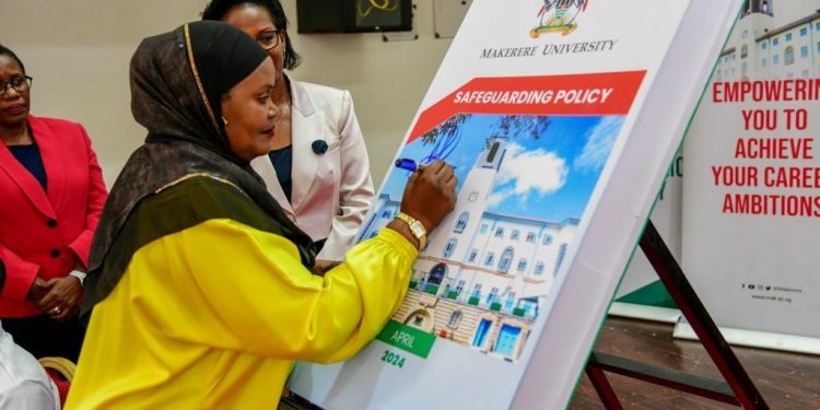 Nakadama signing on the dummy of the policy as other officials look on.
