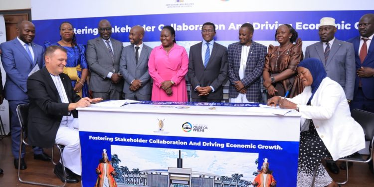 Guillaume DULOUT, the Managing Director of EACOP and Owek. Mariam Nkalubo Mayanja, the Project Lead for the Kibira Kya Kabaka project, sign the MOU that will facilitate the growing of trees as the Katikiro of Buganda and other officials look on.