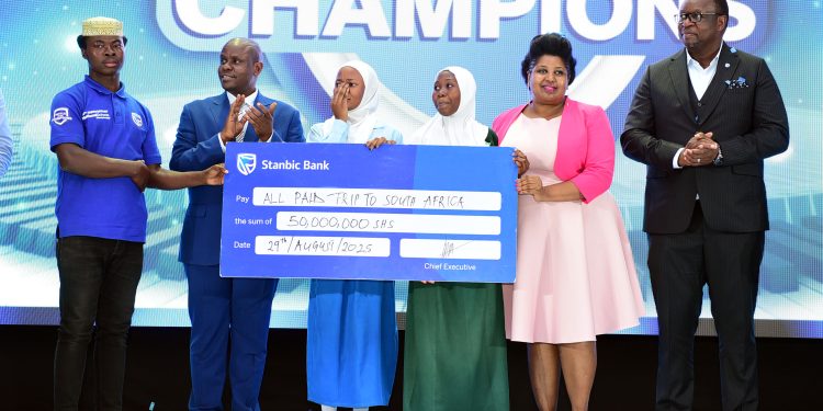 Mumba-Kalifungwa-R-Stanbic-Bank-Chief-Executive-together-with-Minister-Balaam-Barugahara-and-PSFUs-Sarah-Kagingo-handing-over-the-travel-dummie-cheque-to-Sumaya-Girls-students