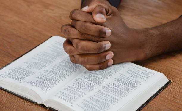 A man praying with holy bible on wooden table. Courtesy photo.