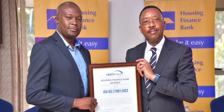Michael Mugabi holding the ISO certificate together with Mike Kamau the Managing Director of Certi Trust during the handover ceremony at the Bank Head offices in Kololo