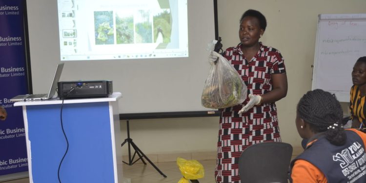 Veronica Nandugwa Brenda CEO,Yoola Kasasilo demonstrates to how she separates organic and inorganic rubbish to the participants