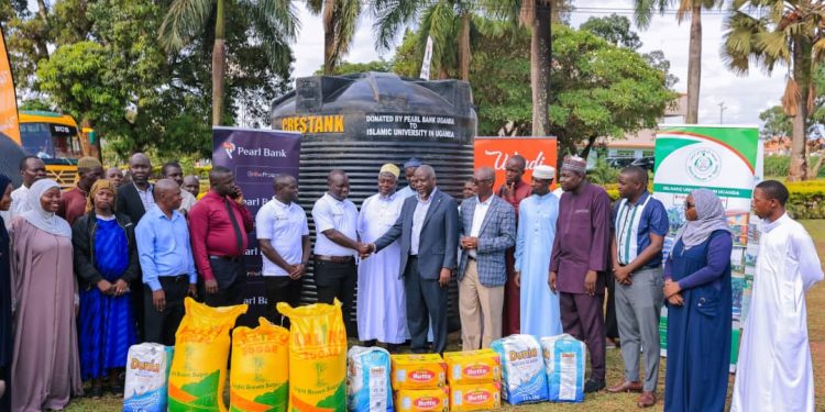 Pearl Bank Mbale Branch Manager Arafat Zaake (6th L) handing over two 10,000 litre water tanks and assorted food items to Assoc. Prof. Ismail Simbwa Gyagenda (7th R), Rector of the Islamic University in Uganda (IUIU) joined by officials from Pearl Bank, IUIU, and Student Representatives as part of Pearl Bank’s Corporate Social Investment (CSI) initiatives pillar of Education, and in recognition of  Women’s month and the Ramadan Season, in collaboration with the Islamic University in Uganda (IUIU) Community Outreach to Summayyah and Abu-Mayanja hostels today, 13th March 2026.