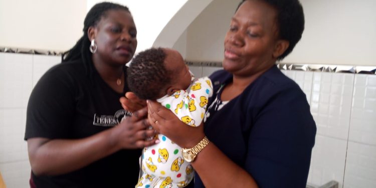 Nasanga Phiona, Administrator at Theresa Home, receives part of the donation from JMS Acting Executive Director Denise Tusiime Mutambi on Wednesday.