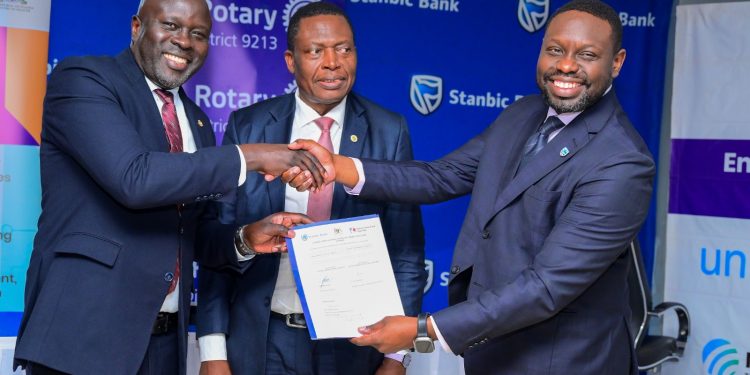 Paul Muganwa ( R), Stanbic Bank Executive Director shakes hands with Rotary District 9213 Governor Dr Gerald Obai, looking on is Dr Charles Olaro the Ministry of Health Director General Health Services.