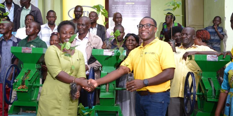 Kalaa Mugosi Women Empowerment Ltd Sandra Nakayenze (L) receives coffee seedlings and processing machines from MTN Uganda MTN Foundation Senior Manager, Bryan Mbasa as other guests looks in Sironko District