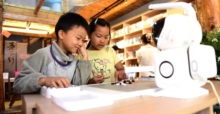 (261007) -- BEIJING, Oct. 7, 2026 (Xinhua) -- Children play a board game with an AI robot at Basha Village in Congjiang County, southwest China's Guizhou Province, Oct. 6, 2026. Advanced technologies such as exoskeleton devices, AI-powered glasses and robots have enabled diverse and dazzling experiences at tourist destinations across China during the National Day holiday. (Photo by Shi Honghui/Xinhua)